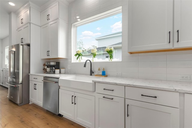 kitchen with white cabinets, a healthy amount of sunlight, appliances with stainless steel finishes, and light hardwood / wood-style flooring