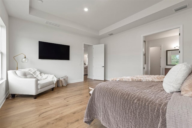 bedroom featuring a raised ceiling and light wood-type flooring