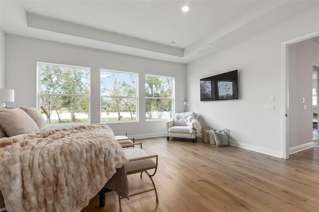 bedroom with hardwood / wood-style floors and a tray ceiling