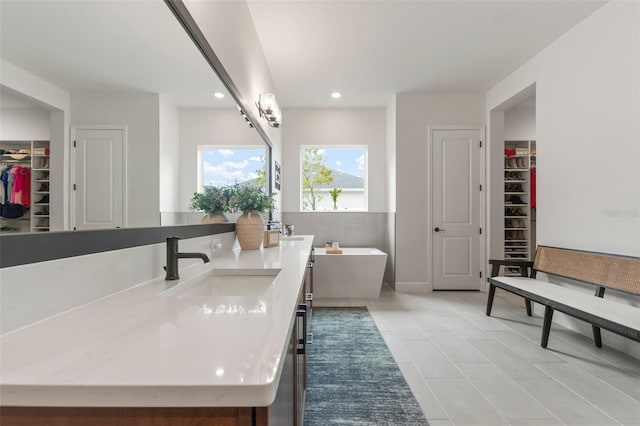 bathroom with tile patterned floors, a washtub, and vanity