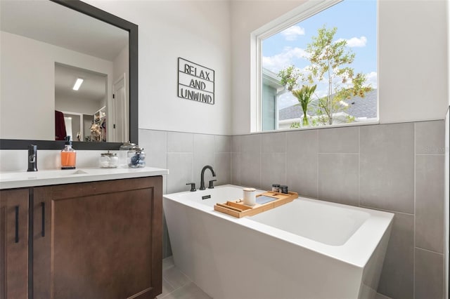 bathroom featuring a bathing tub, vanity, tile patterned floors, and tile walls