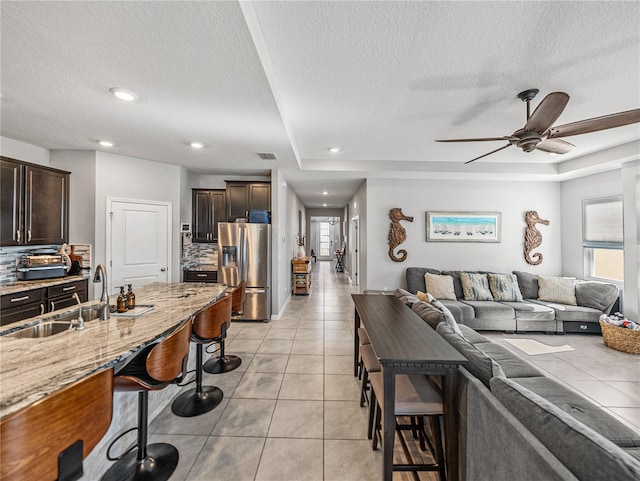 interior space featuring light tile patterned flooring, decorative backsplash, dark brown cabinets, and stainless steel fridge