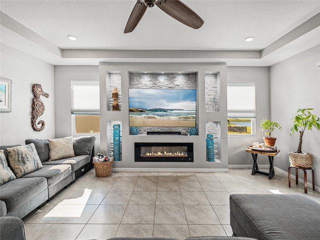 living room with ceiling fan, a wealth of natural light, a textured ceiling, and light tile patterned floors