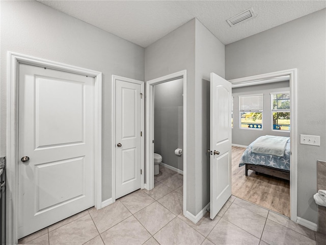 bathroom featuring toilet, tile patterned floors, and a textured ceiling