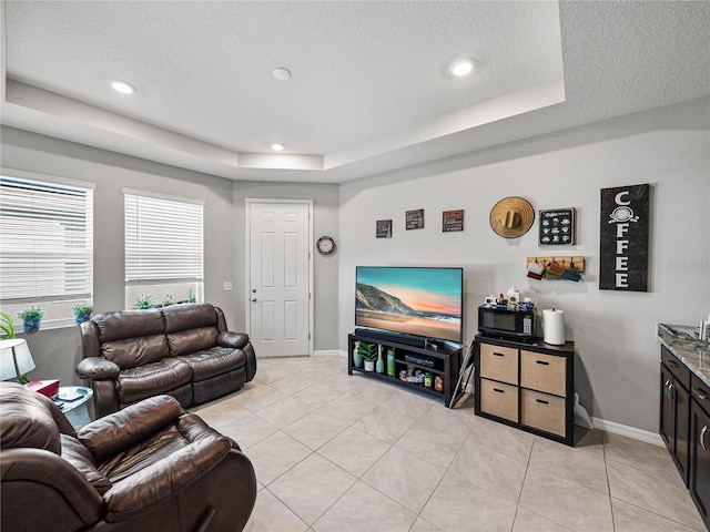 living room featuring a raised ceiling, light tile patterned floors, and a textured ceiling