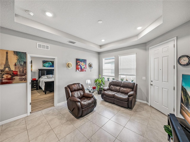 tiled living room featuring sink, a raised ceiling, and a textured ceiling