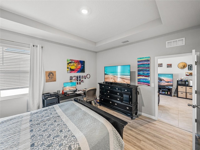 bedroom featuring light hardwood / wood-style flooring and a raised ceiling