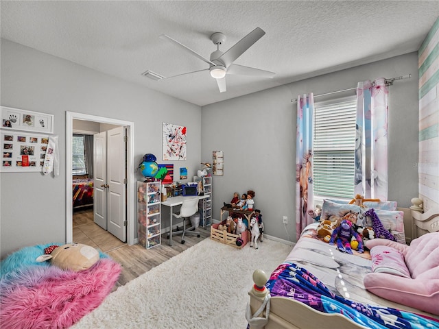 bedroom with white refrigerator, a textured ceiling, ceiling fan, and light wood-type flooring