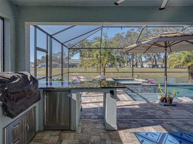 view of patio featuring a lanai, an outdoor bar, a pool with hot tub, area for grilling, and a water view