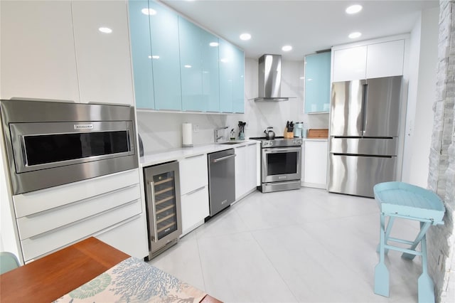 kitchen featuring wall chimney exhaust hood, white cabinetry, light tile patterned floors, appliances with stainless steel finishes, and beverage cooler