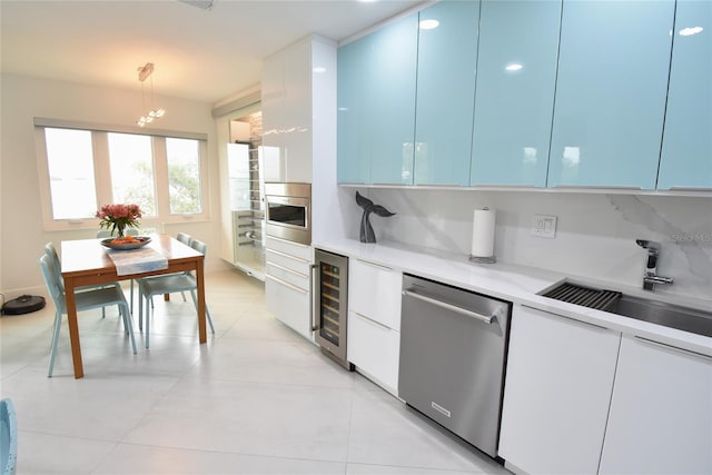 kitchen with dishwasher, sink, white cabinets, beverage cooler, and hanging light fixtures