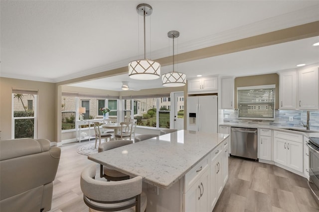 kitchen featuring appliances with stainless steel finishes, decorative light fixtures, a kitchen island, and white cabinetry