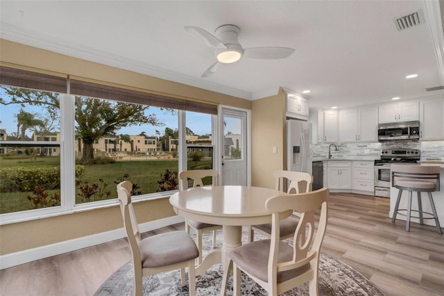 dining space featuring ceiling fan, sink, light hardwood / wood-style floors, and ornamental molding