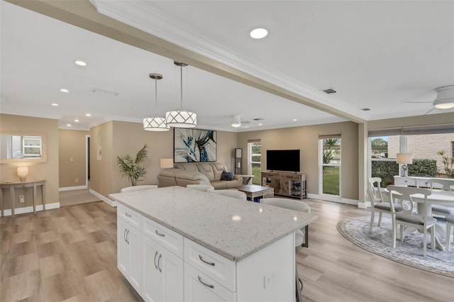 kitchen featuring pendant lighting, white cabinets, light hardwood / wood-style flooring, ceiling fan, and light stone counters