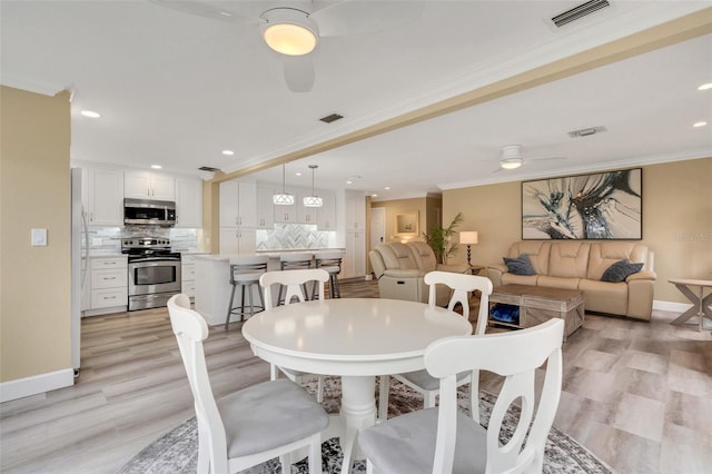 dining room featuring ceiling fan, crown molding, and light hardwood / wood-style flooring