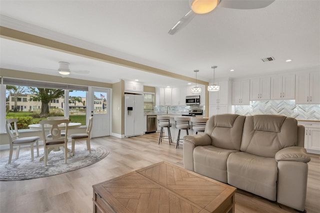 living room featuring ceiling fan, light hardwood / wood-style floors, and ornamental molding