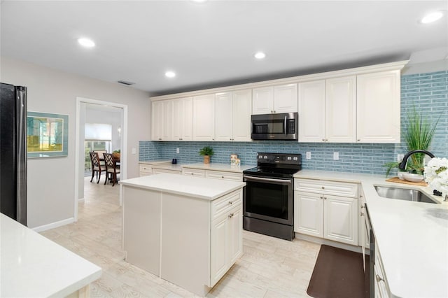 kitchen featuring a kitchen island, appliances with stainless steel finishes, sink, white cabinets, and decorative backsplash