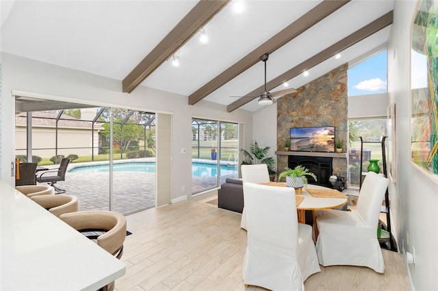 dining room with high vaulted ceiling, a fireplace, beamed ceiling, ceiling fan, and light hardwood / wood-style floors