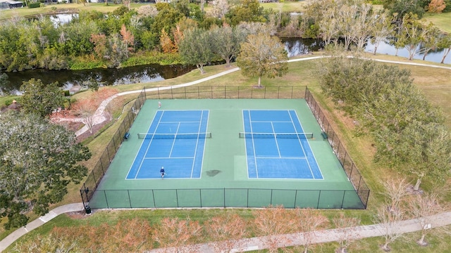 view of tennis court with a water view and a lawn