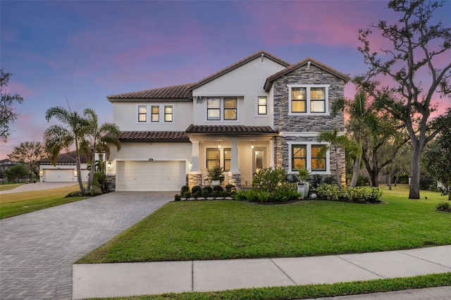 view of front of house featuring a yard, an attached garage, stucco siding, stone siding, and decorative driveway