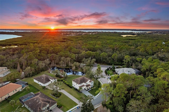 aerial view at dusk featuring a water view