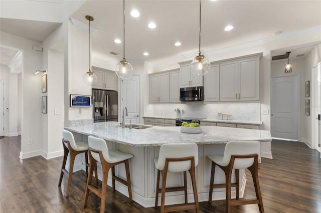 kitchen with a breakfast bar, a sink, backsplash, dark wood finished floors, and stainless steel appliances