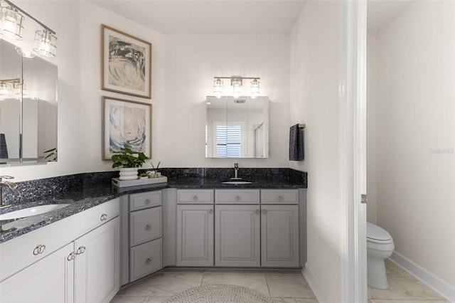 bathroom with marble finish floor, two vanities, and a sink