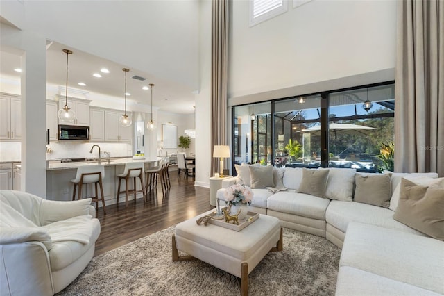 living area featuring a high ceiling, recessed lighting, dark wood-style floors, and baseboards