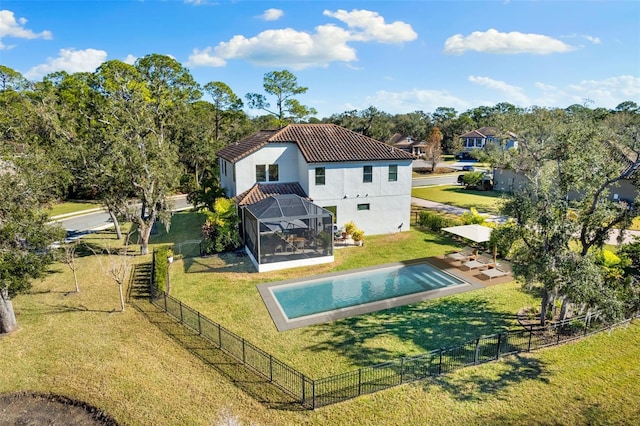 back of property with a fenced backyard, glass enclosure, a tile roof, and a yard