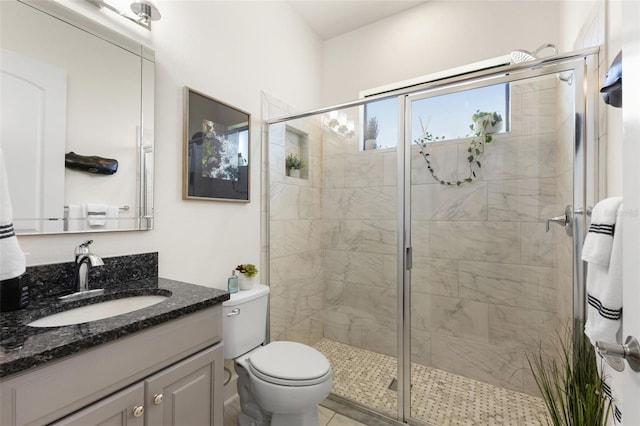 bathroom with vanity, a shower stall, and toilet