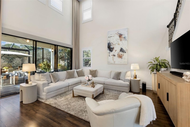 living room featuring a high ceiling and dark wood-style floors