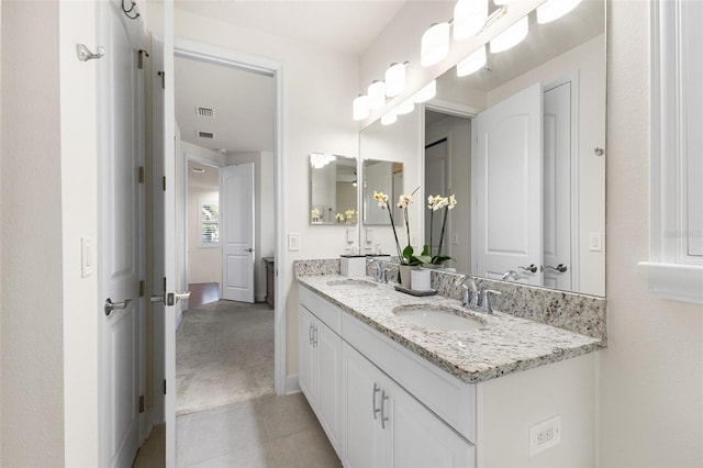 bathroom with double vanity, baseboards, tile patterned floors, and a sink