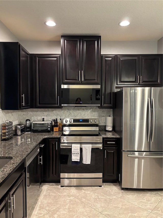 kitchen featuring decorative backsplash, appliances with stainless steel finishes, dark stone counters, and light tile patterned flooring