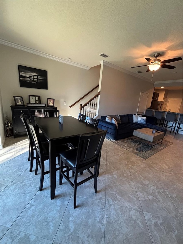 dining area featuring ceiling fan, a textured ceiling, and ornamental molding