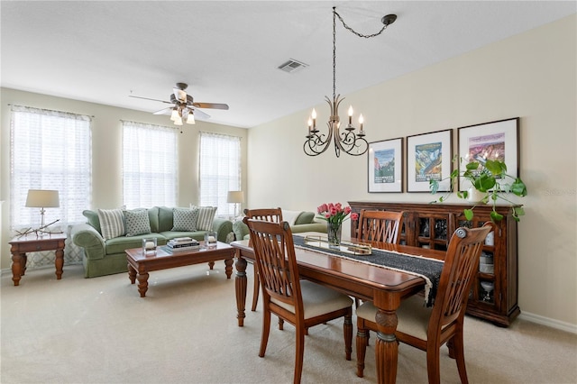 dining area with ceiling fan with notable chandelier and light carpet