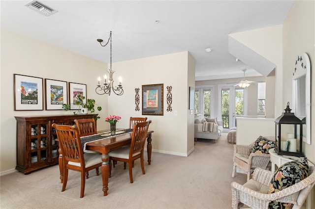 dining space with light colored carpet, french doors, and ceiling fan with notable chandelier