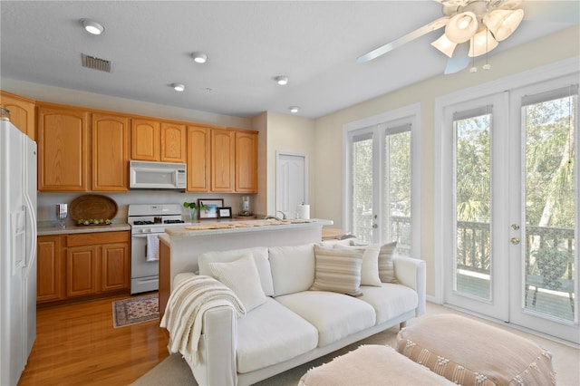 kitchen featuring white appliances, light hardwood / wood-style floors, ceiling fan, french doors, and a kitchen island