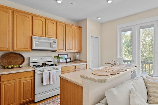 kitchen with white appliances, a center island, a kitchen bar, and sink