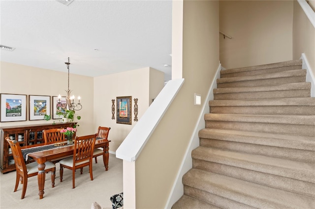 staircase featuring an inviting chandelier and carpet