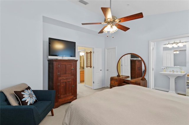 bedroom featuring ceiling fan, ensuite bathroom, light carpet, and sink