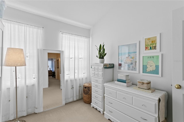 bedroom featuring light colored carpet and vaulted ceiling