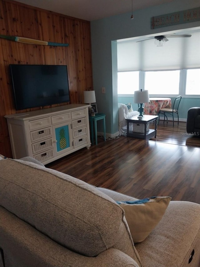 living room with dark hardwood / wood-style flooring and wooden walls