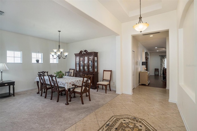 carpeted dining space with a notable chandelier and a tray ceiling