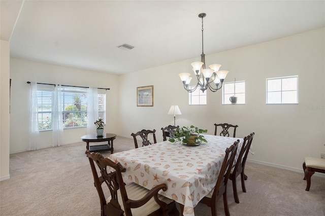 dining space featuring light carpet and an inviting chandelier