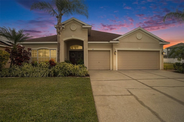 view of front of property with a garage and a yard