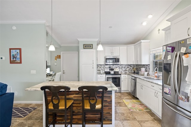 kitchen featuring a breakfast bar, stainless steel appliances, crown molding, pendant lighting, and white cabinets