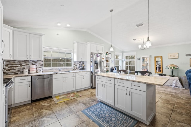 kitchen with appliances with stainless steel finishes, backsplash, pendant lighting, white cabinets, and lofted ceiling