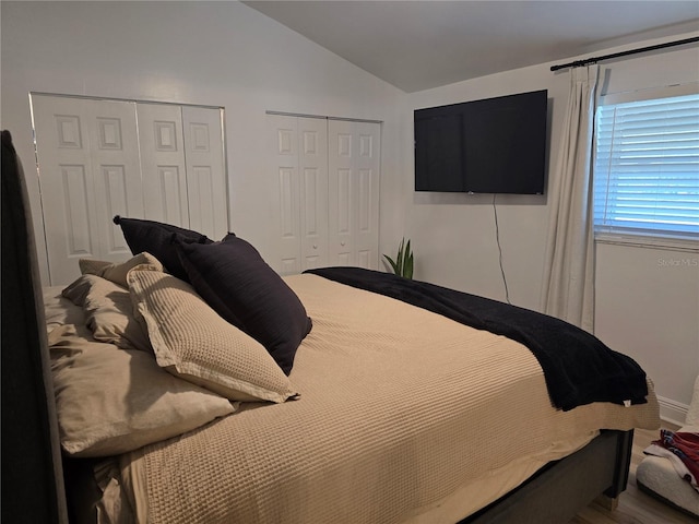 bedroom featuring multiple closets and vaulted ceiling