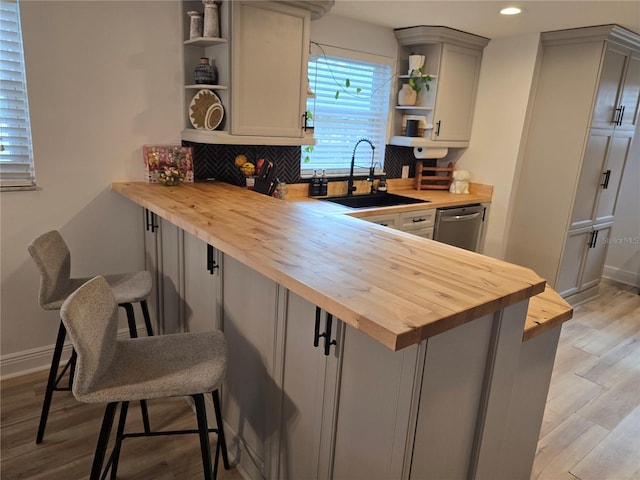 kitchen featuring a kitchen bar, wooden counters, gray cabinetry, and sink