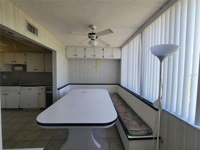 kitchen with dishwasher, sink, dark tile patterned flooring, and a textured ceiling